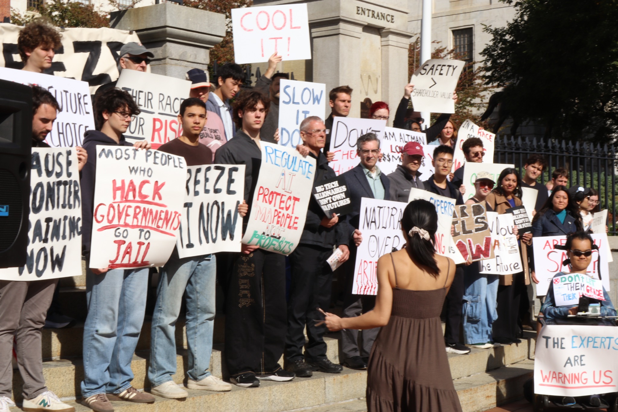 A group of rally participants holding AI safety signs on the Massachusetts State House steps